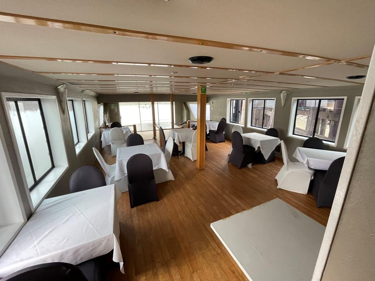 a room with tables and chairs aboard MAGIC MOMENT Yacht for Sale