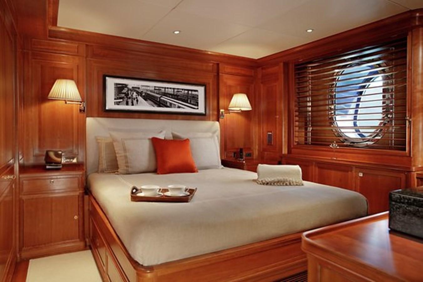 a bed with a white comforter and pillows in a room with wood walls and a wood panel aboard LA LUNA Yacht for Sale