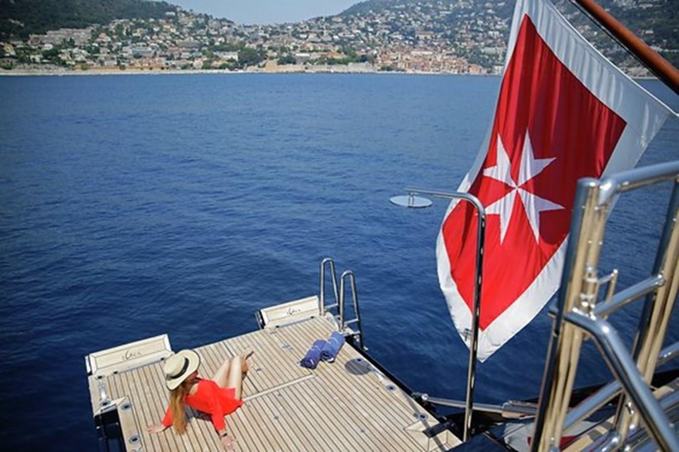 a person sitting on a boat with a flag on the front aboard LA LUNA Yacht for Sale