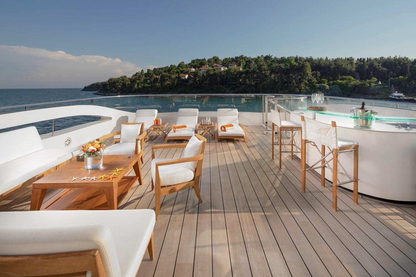 a deck with chairs and tables on it by a pool aboard STERN Yacht for Sale