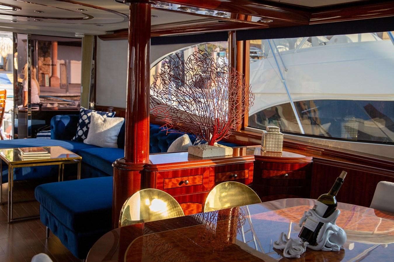 a room with a blue couch and a window with a curtain aboard LAZZARA 80' Yacht for Sale