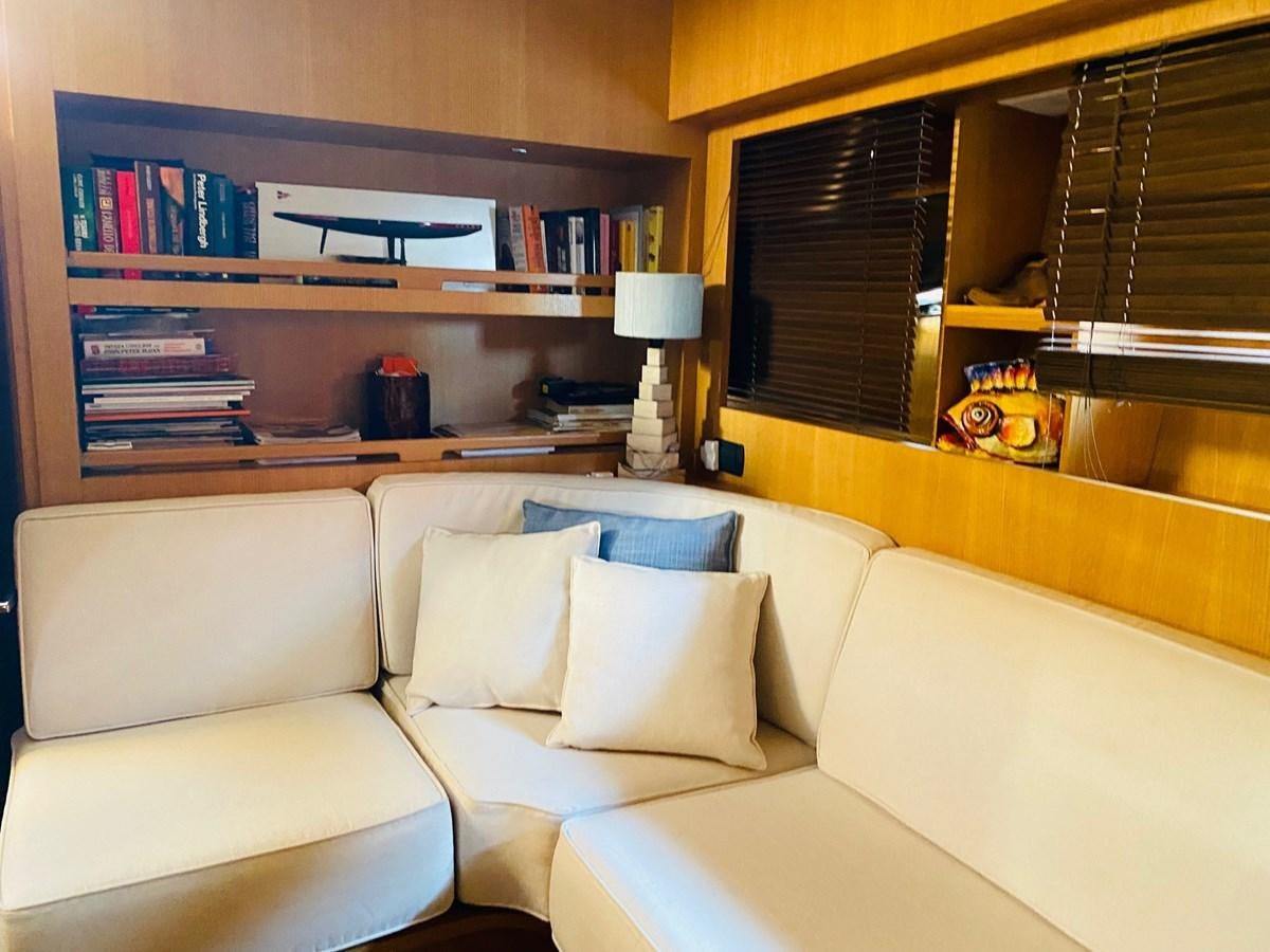 a living room with a white couch and a shelf with books aboard DEA Yacht for Sale