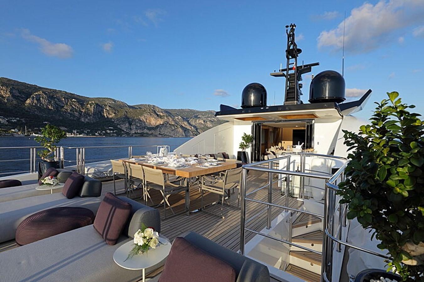 a deck with a grill and a table with chairs and plants on it aboard NEXT Yacht for Sale