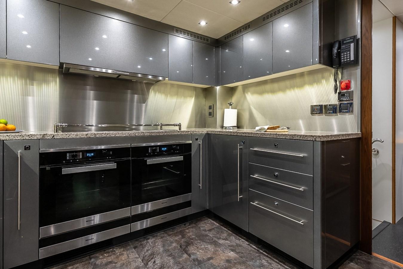a kitchen with black appliances aboard INSIGNIA Yacht for Sale