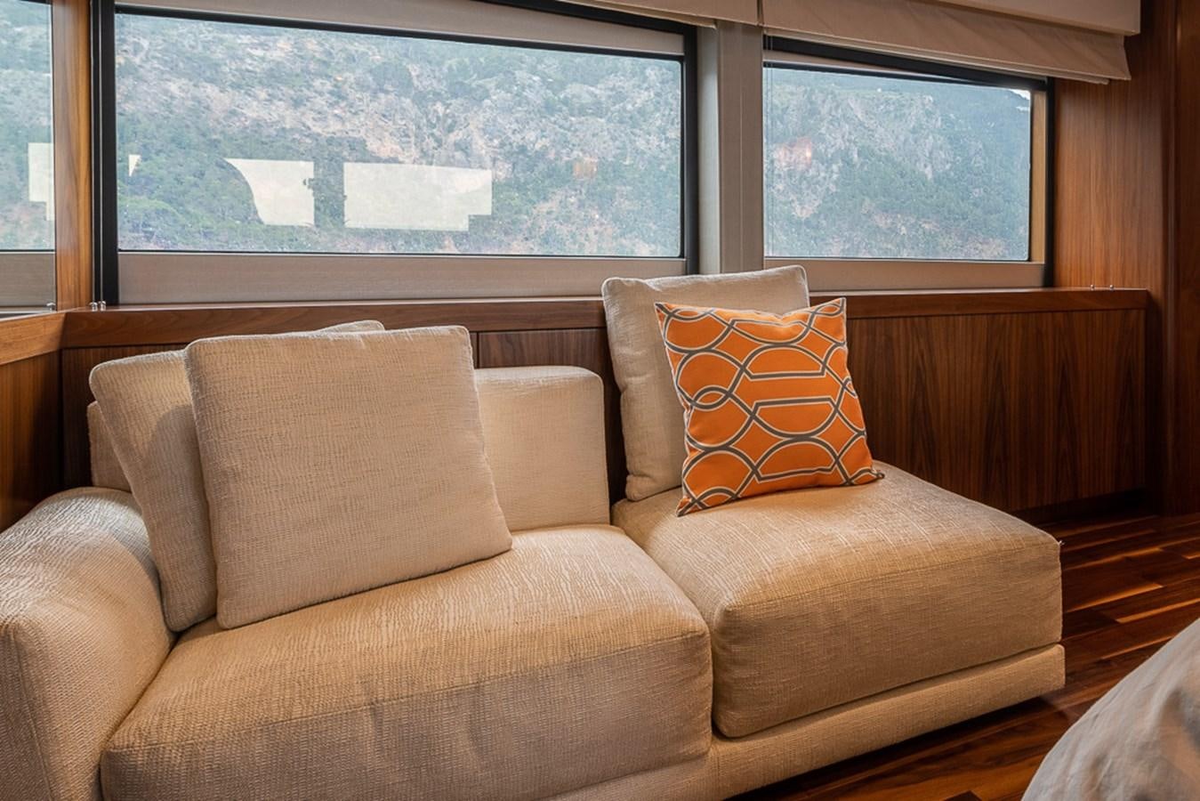 a couch with pillows in front of a window aboard INSIGNIA Yacht for Sale