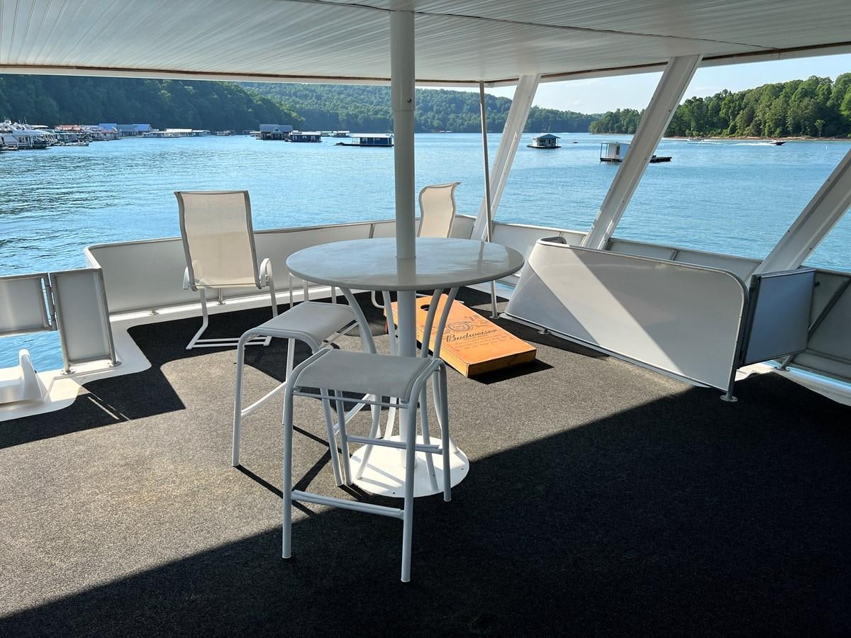 a table and chairs on a deck overlooking a body of water aboard 2010/1995 STARDUST 20 X 95WB NLST Yacht for Sale