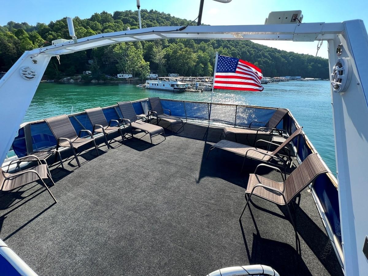 a boat on a dock with chairs and a flag on the side aboard 2010/1995 STARDUST 20 X 95WB NLST Yacht for Sale