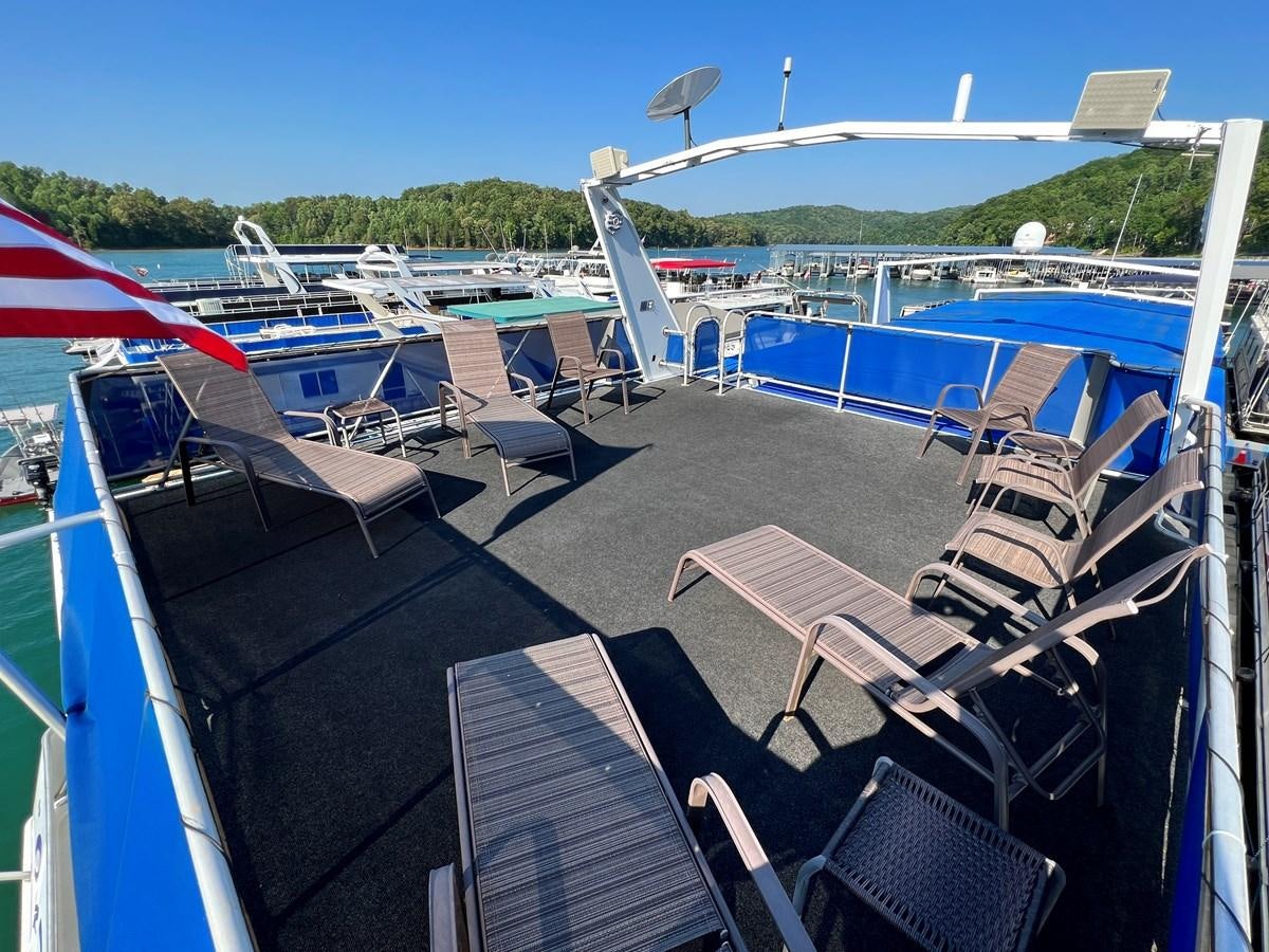 a deck with chairs and tables on it and an airplane in the background aboard 2010/1995 STARDUST 20 X 95WB NLST Yacht for Sale