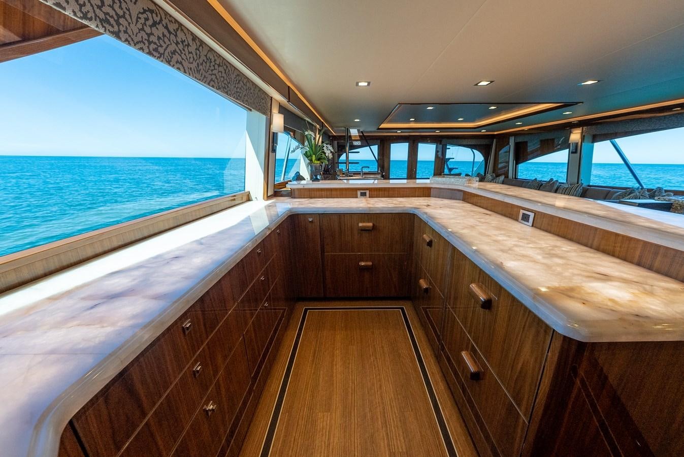 a long wooden kitchen with a large window and wood cabinets aboard ANOTHER DAY IN PARADISE Yacht for Sale