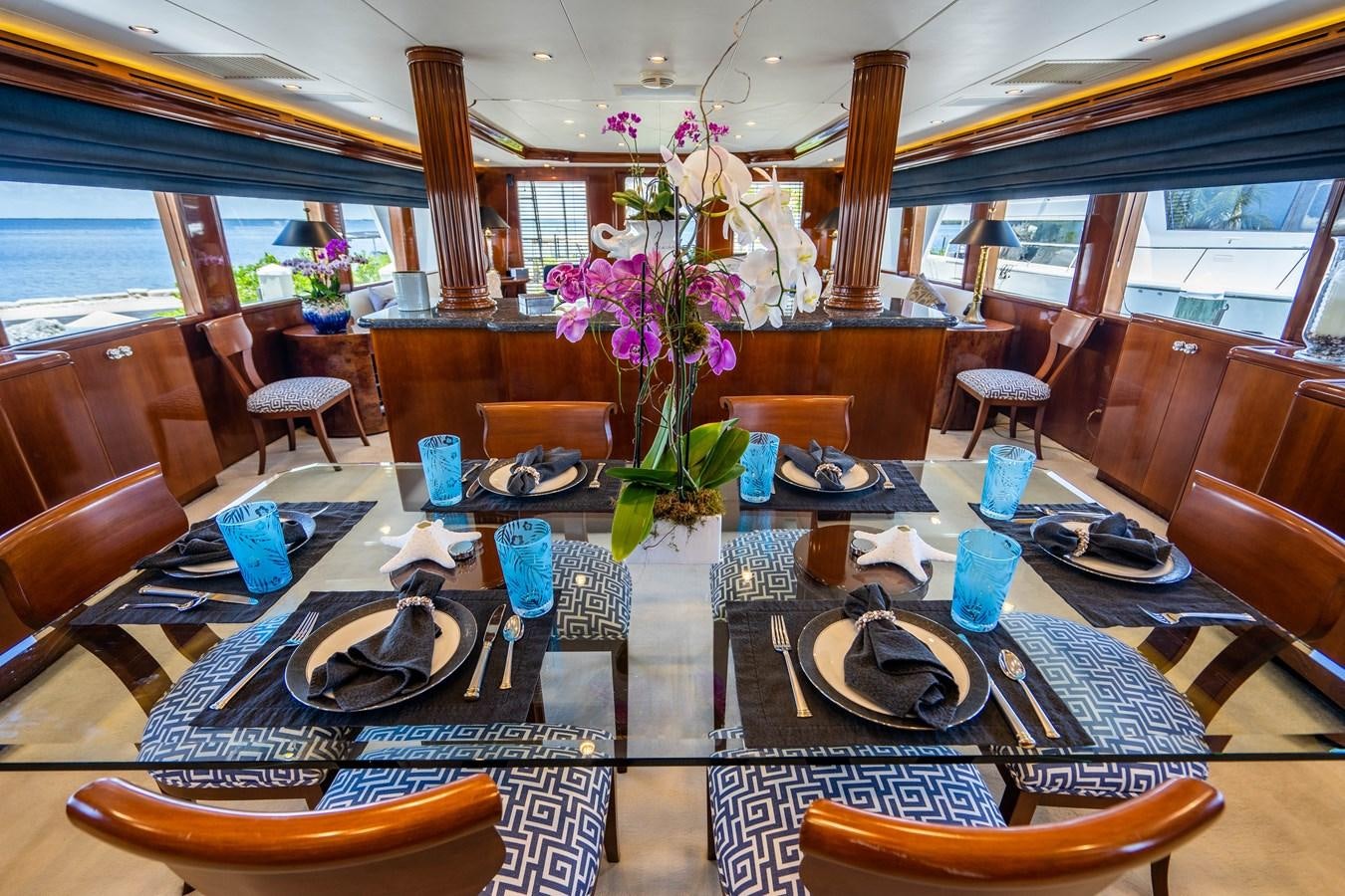 a room with a table chairs and flowers aboard PURA VIDA Yacht for Sale