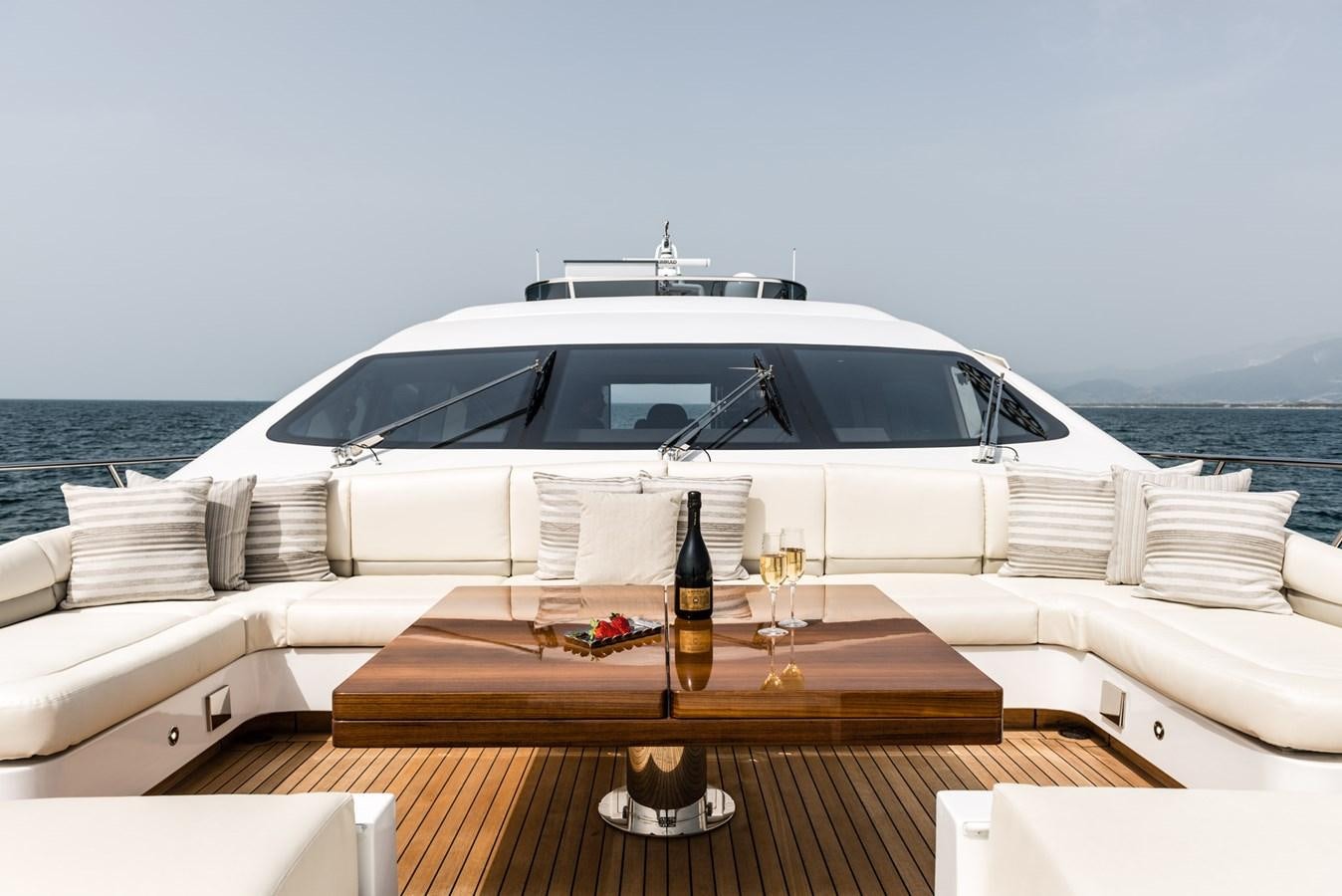 a white yacht with a glass of beer on a wooden table on a boat aboard MINE SET Yacht for Sale