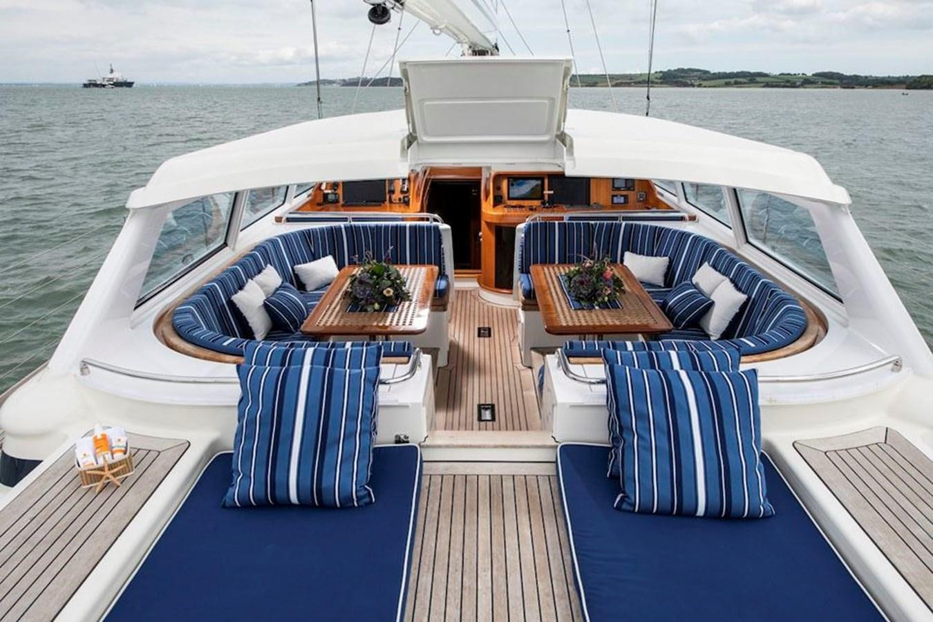 a large white boat with blue chairs on a dock aboard CHARLATAN Yacht for Sale