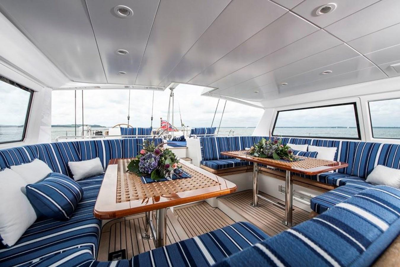 a room with a table and couches aboard CHARLATAN Yacht for Sale
