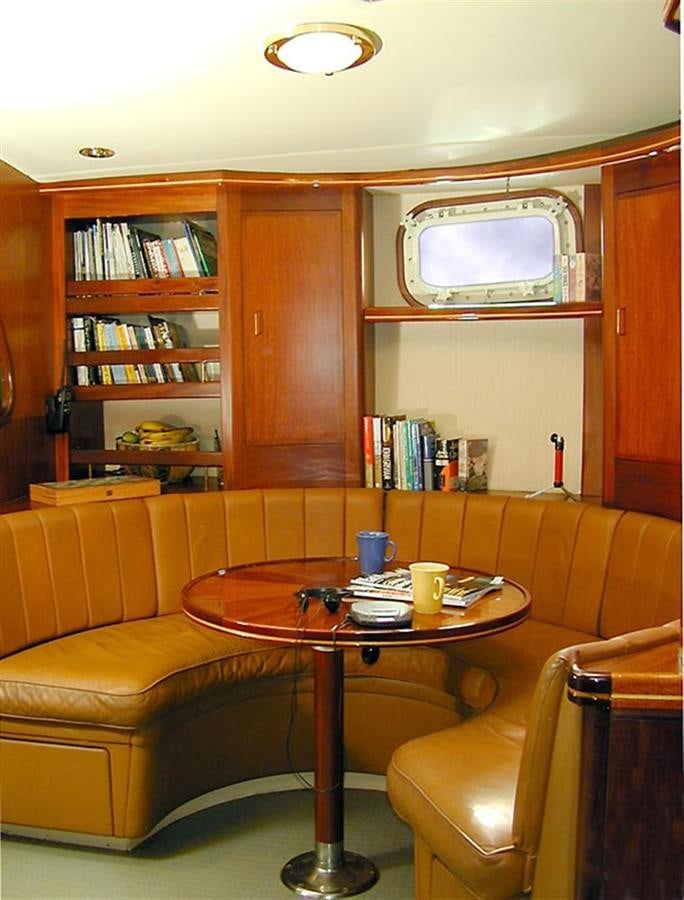 a living room with a table and couches aboard AURASTEL Yacht for Sale