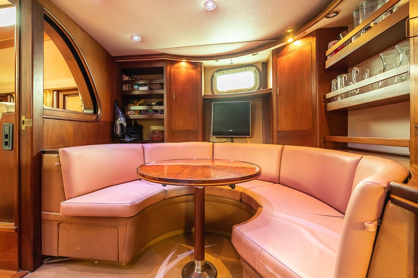 a living room with a table and couches aboard AURASTEL Yacht for Sale