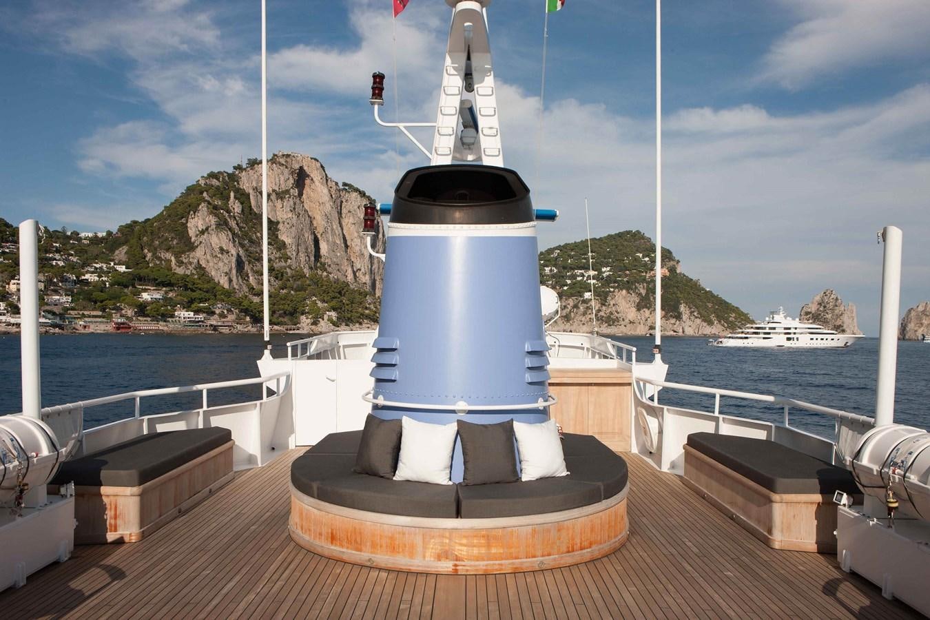 a white and black lighthouse on a dock with a large rock and water in the background aboard ICE LADY Yacht for Sale