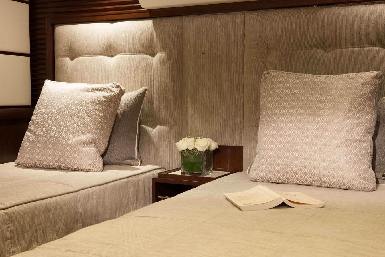 a bed with pillows and a vase of flowers on it aboard ICE LADY Yacht for Sale