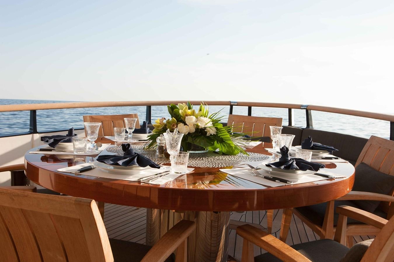 a table with a plate of food and flowers on it aboard ICE LADY Yacht for Sale