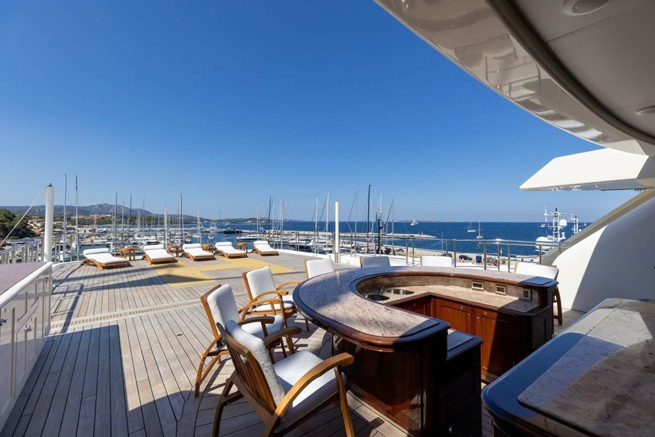 a deck with chairs and tables on it by a body of water aboard PURE Yacht for Sale