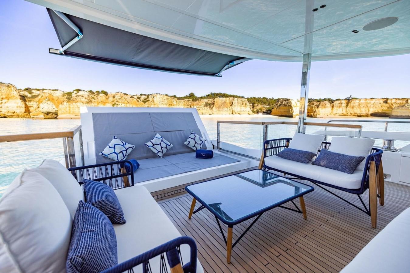 a large white lounge chair next to a blue table and a blue couch aboard SUNSEEKER 100 Yacht for Sale