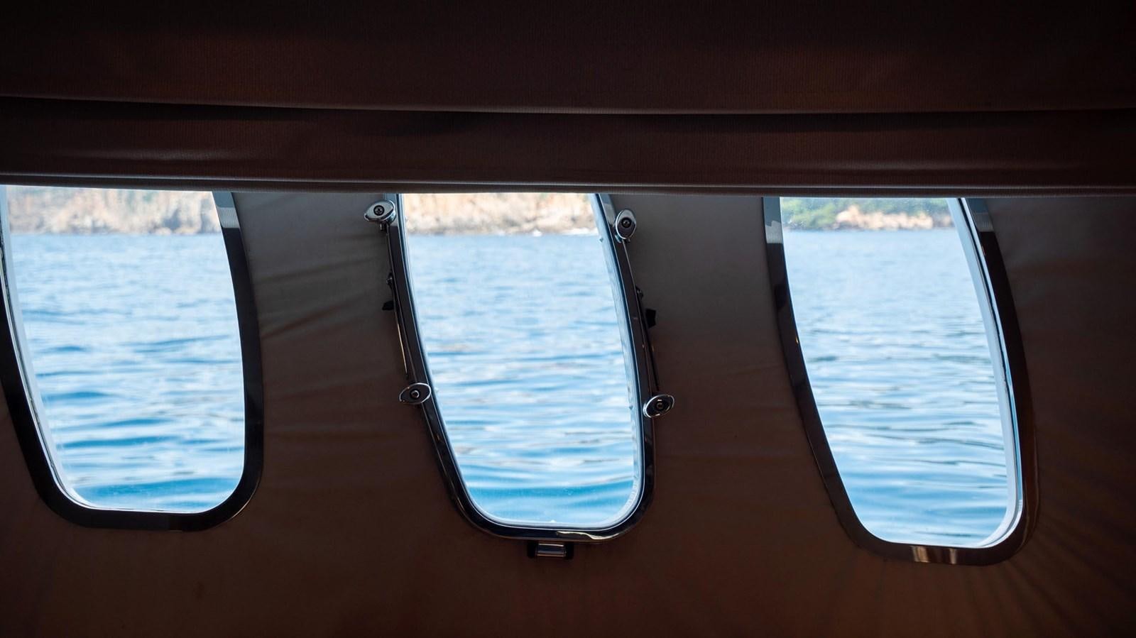 a window with a view of the water and land below aboard LUCKY BEAR Yacht for Sale