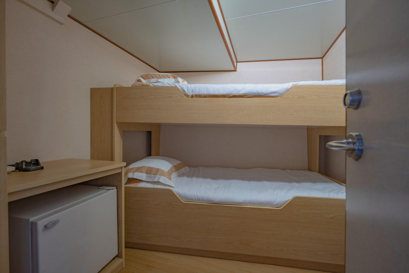 a bed with a desk and a closet aboard SOUTHERN CROSS Yacht for Charter
