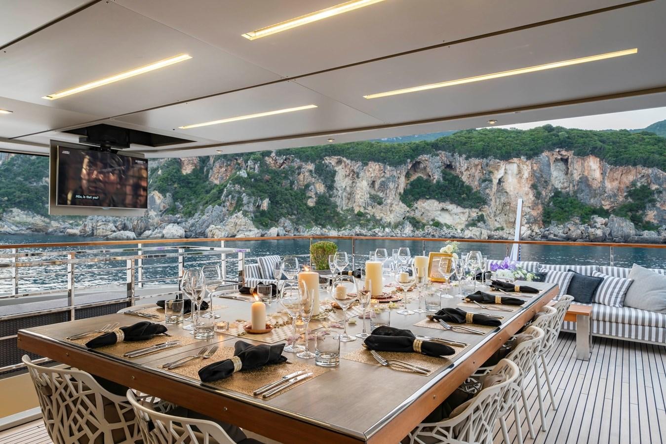a large dining table with chairs and a large wall of water behind it aboard MAVERICK Yacht for Sale