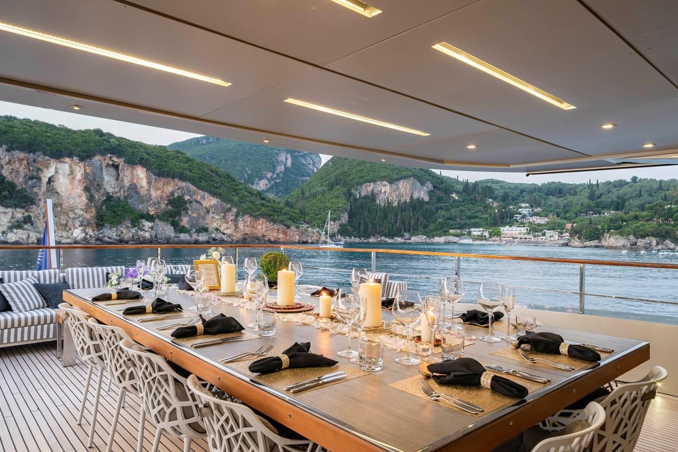 a table set for a meal on a deck overlooking a body of water aboard MAVERICK Yacht for Sale