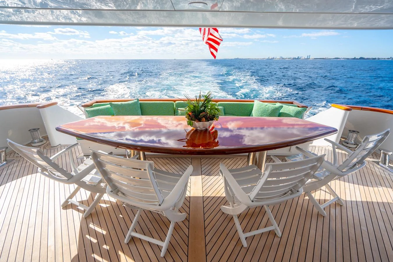 a table set with chairs and a flag on a balcony overlooking a beach aboard HOG HEAVEN Yacht for Sale