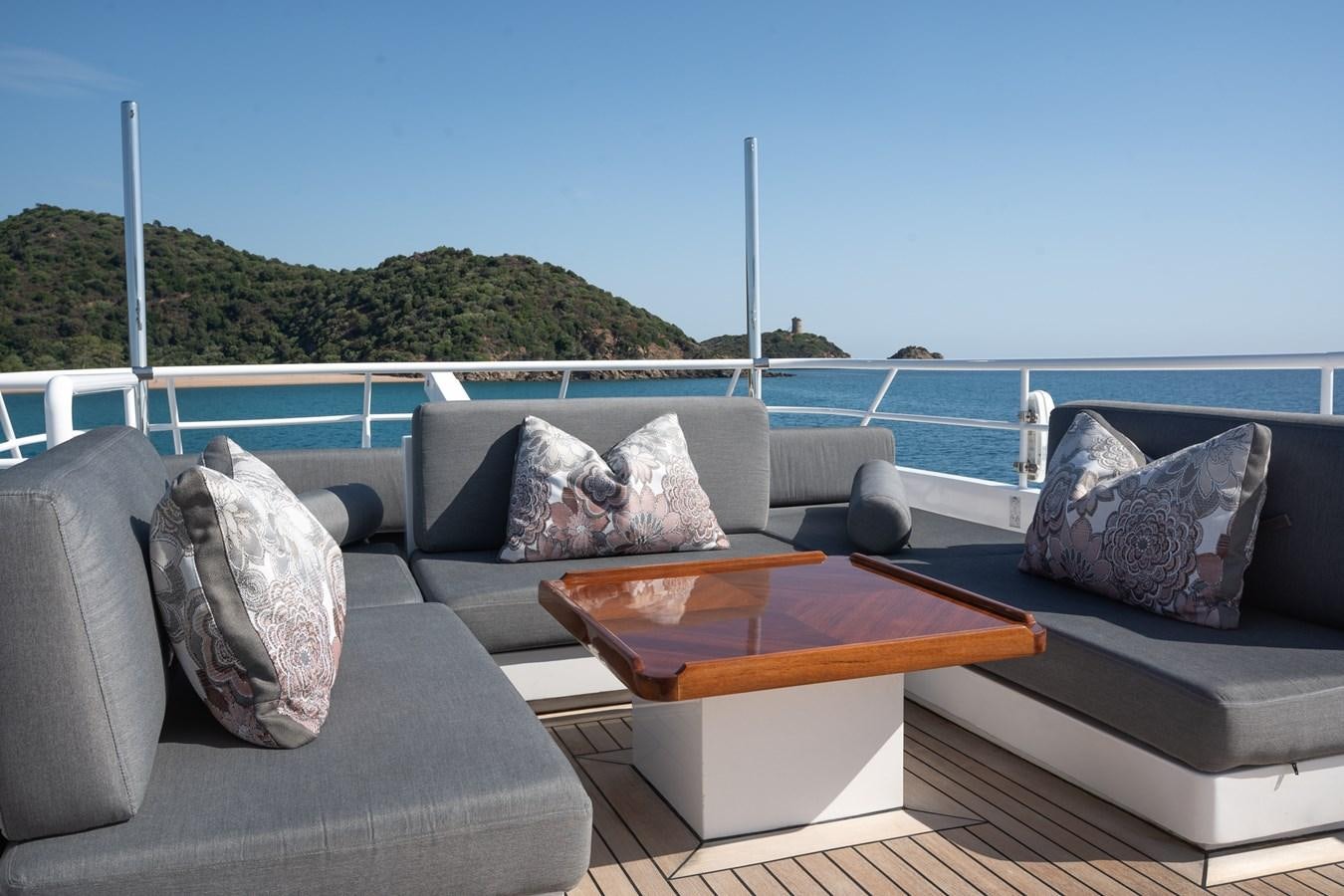 a couch and a table on a deck overlooking a body of water aboard BERZINC Yacht for Charter