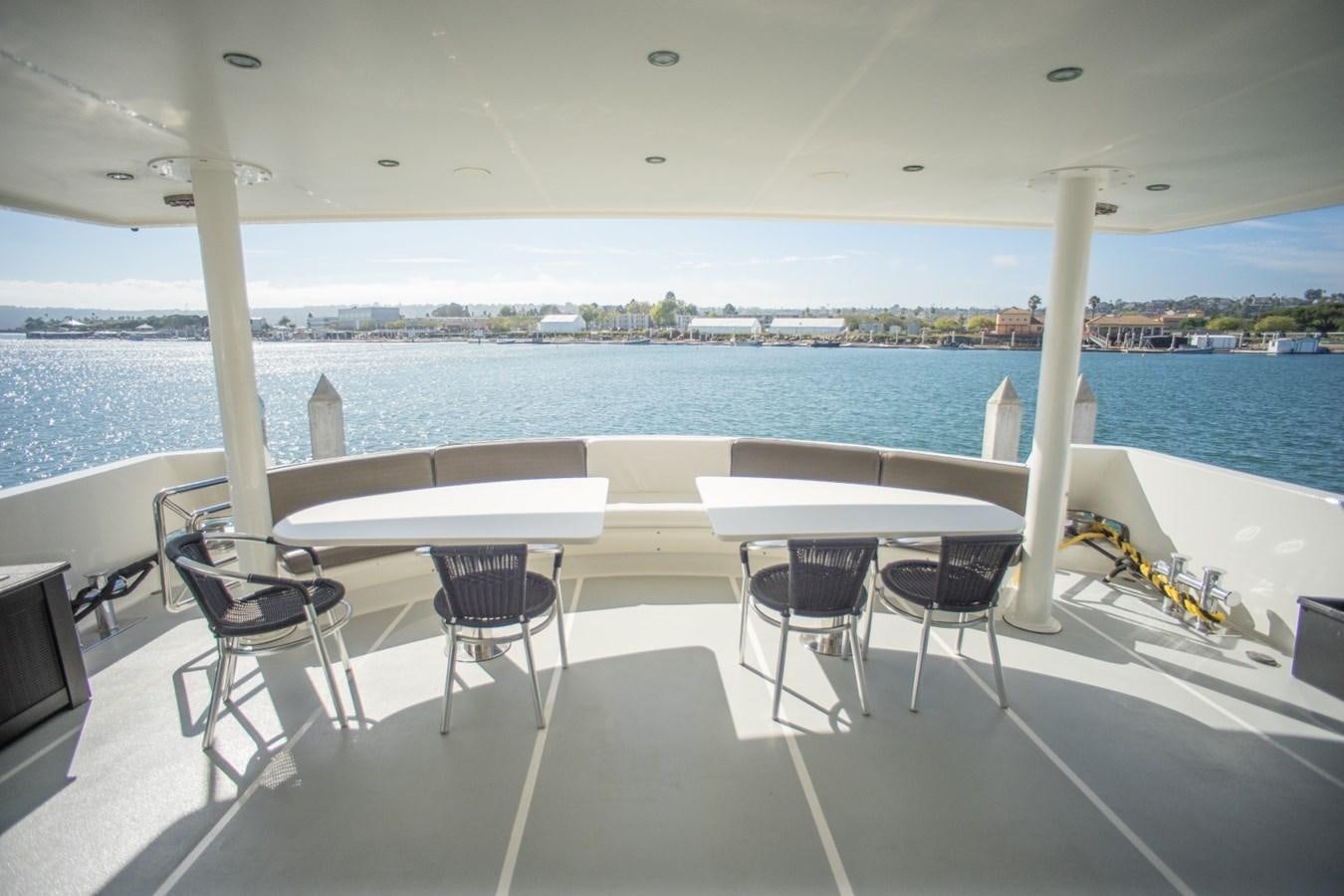 a table and chairs on a deck overlooking a beach aboard JACO Yacht for Sale
