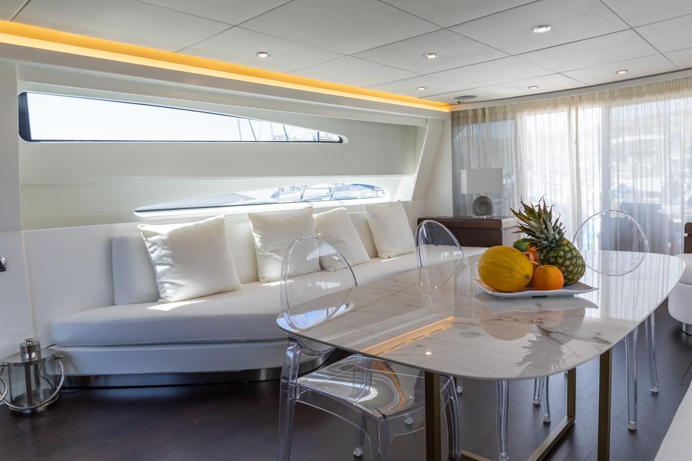 a white living room with a white couch and a table with chairs aboard VEVEKOS Yacht for Sale