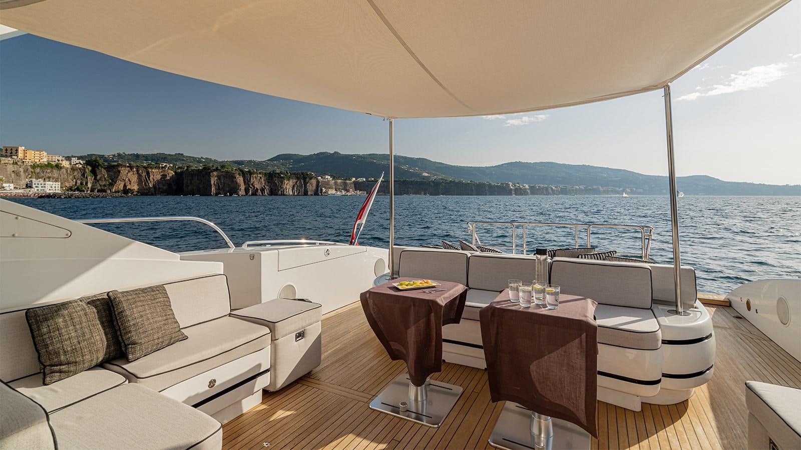 a room with a table and chairs on it and a body of water in the background aboard DEVA I Yacht for Sale
