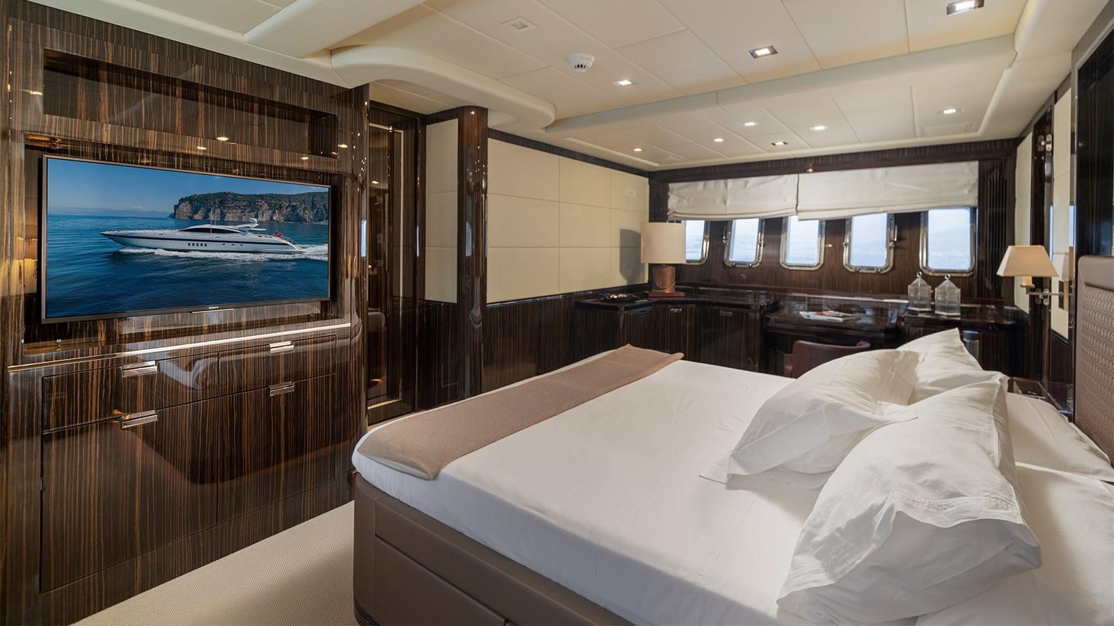 a room with a bed and a tv on the wall aboard DEVA I Yacht for Sale