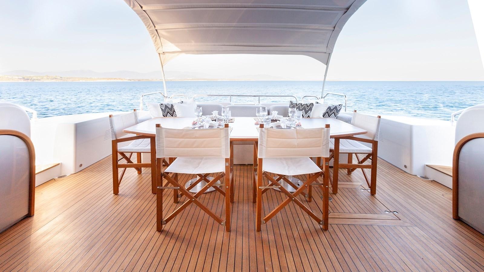 a table and chairs on a deck overlooking the ocean aboard KIDI ONE Yacht for Sale