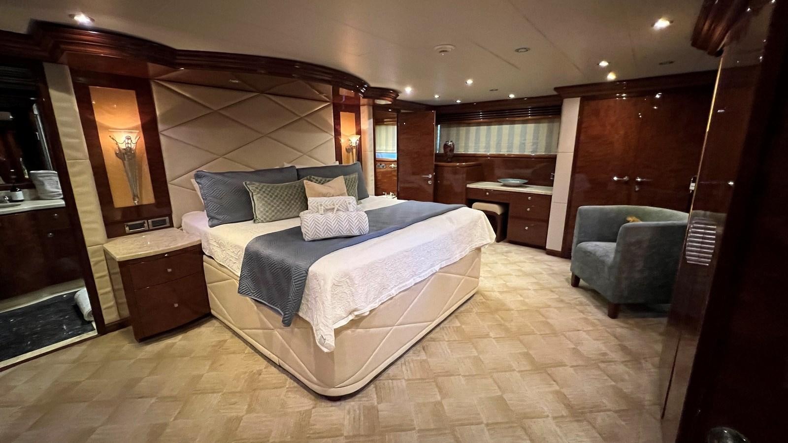 a large bedroom with a bed and a chair aboard MISSY B II Yacht for Sale