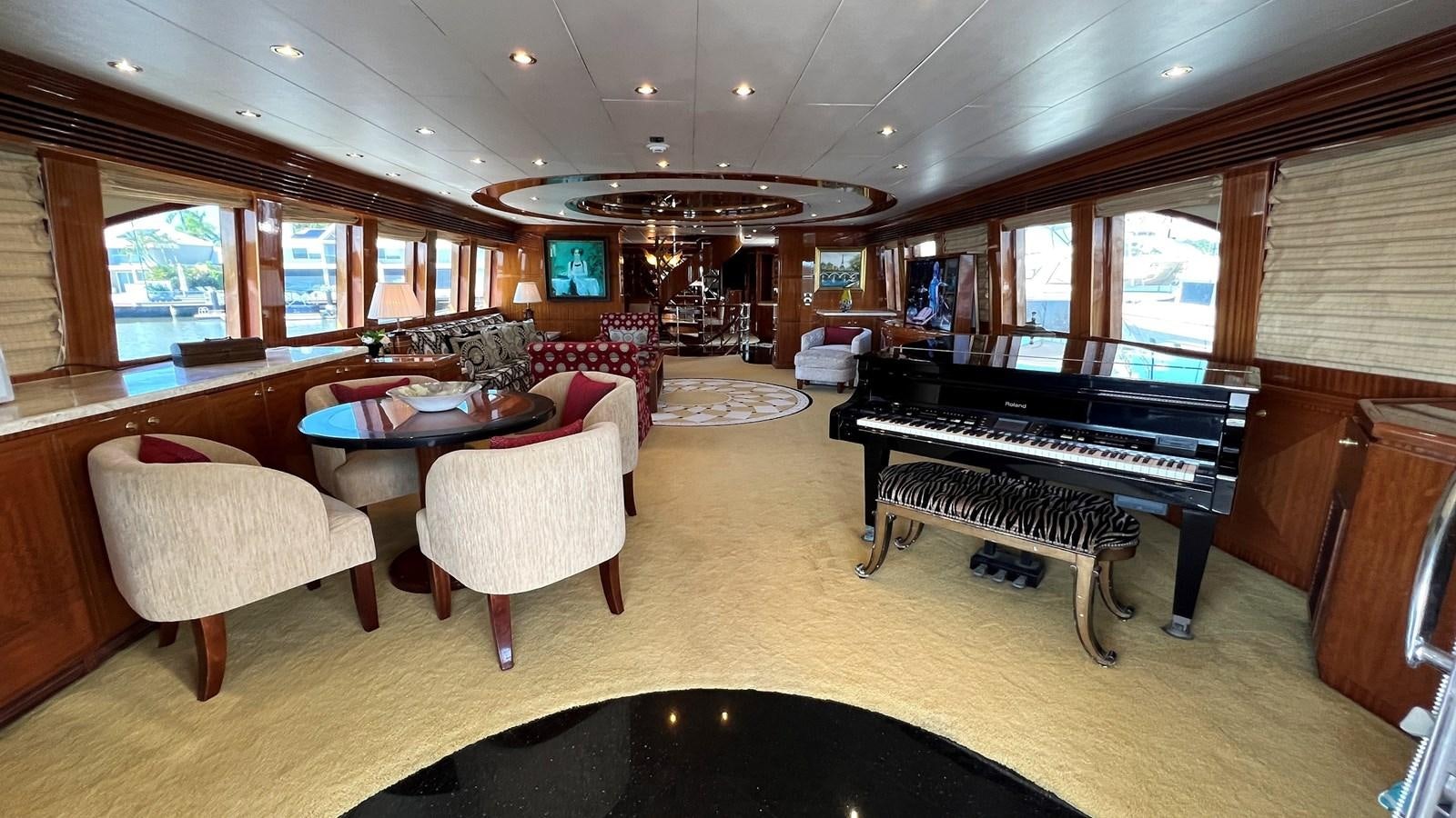 a room with a piano and a table and chairs aboard MISSY B II Yacht for Sale