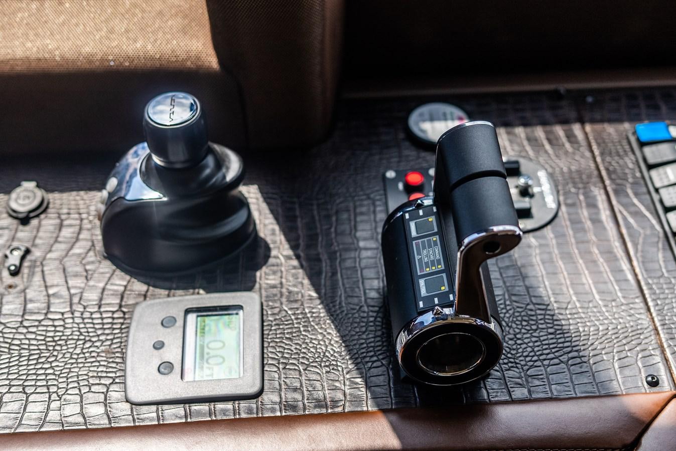 a black electronic device with a black case and a black rectangular object on a brown surface aboard DAYS LIKE THIS Yacht for Sale