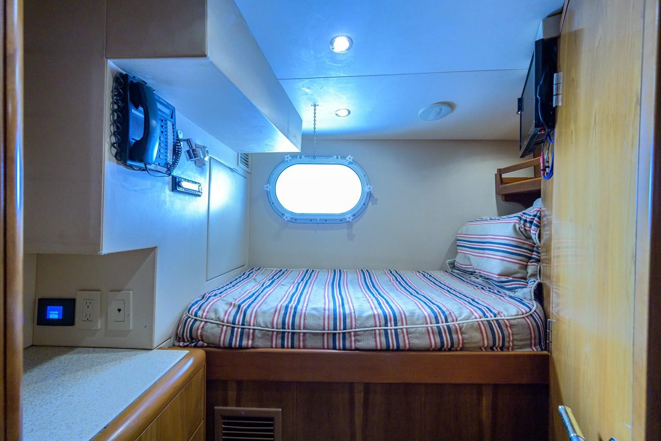 a bed with a desk and a computer on the wall aboard SAR Yacht for Sale