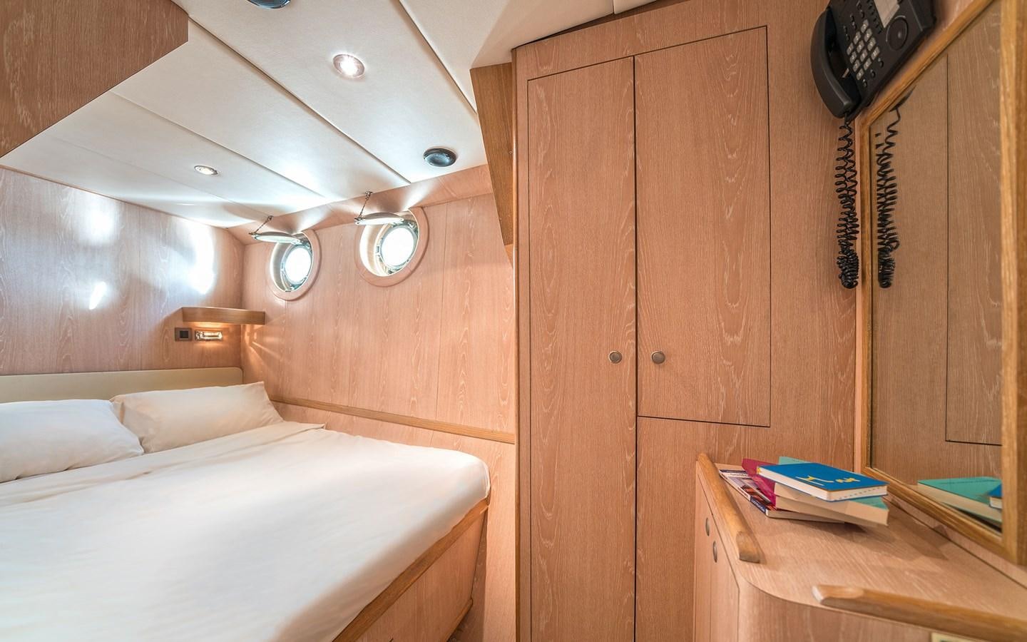 a wooden room with a bed and a wooden cabinet aboard LACROMA Yacht for Sale