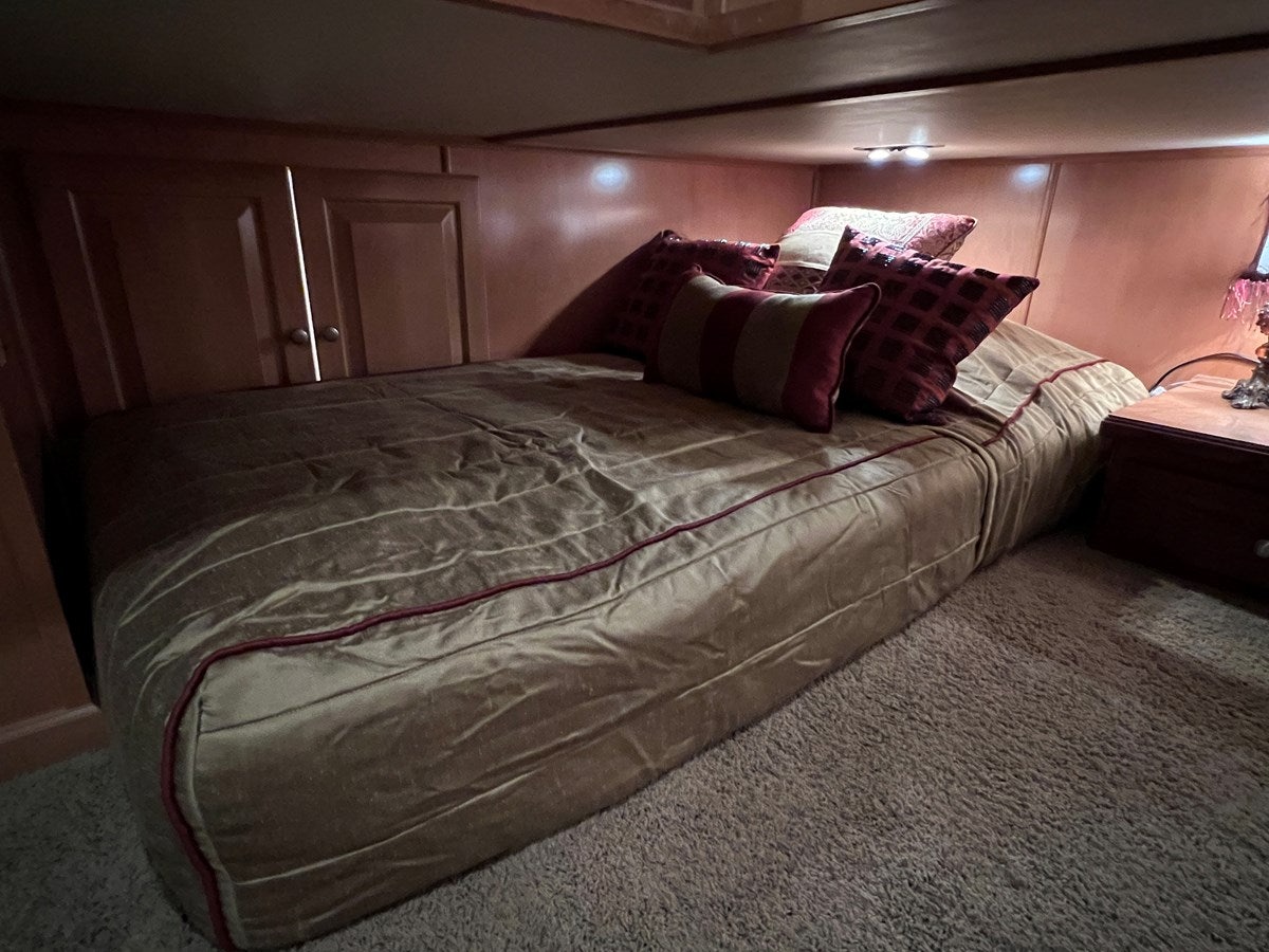 a bed with a red and white comforter and pillows aboard 2007 STARDUST 19 X 86WB NLCG Yacht for Sale