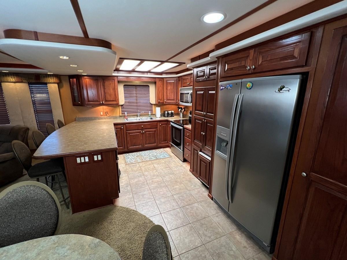 a kitchen with a refrigerator and a table aboard 2007 STARDUST 19 X 86WB NLCG Yacht for Sale