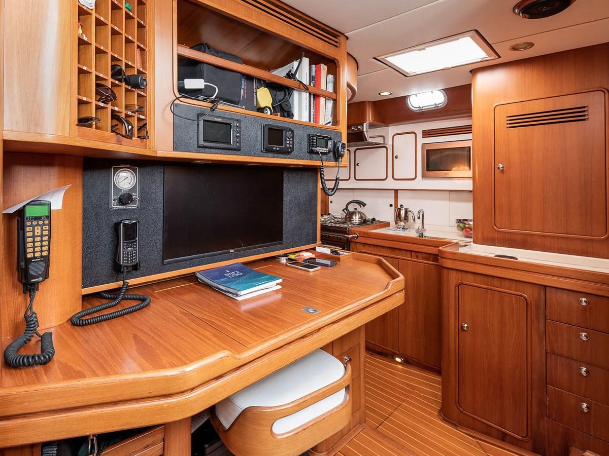 a room with a tv and a shelf with books aboard VENTUROUS Yacht for Sale