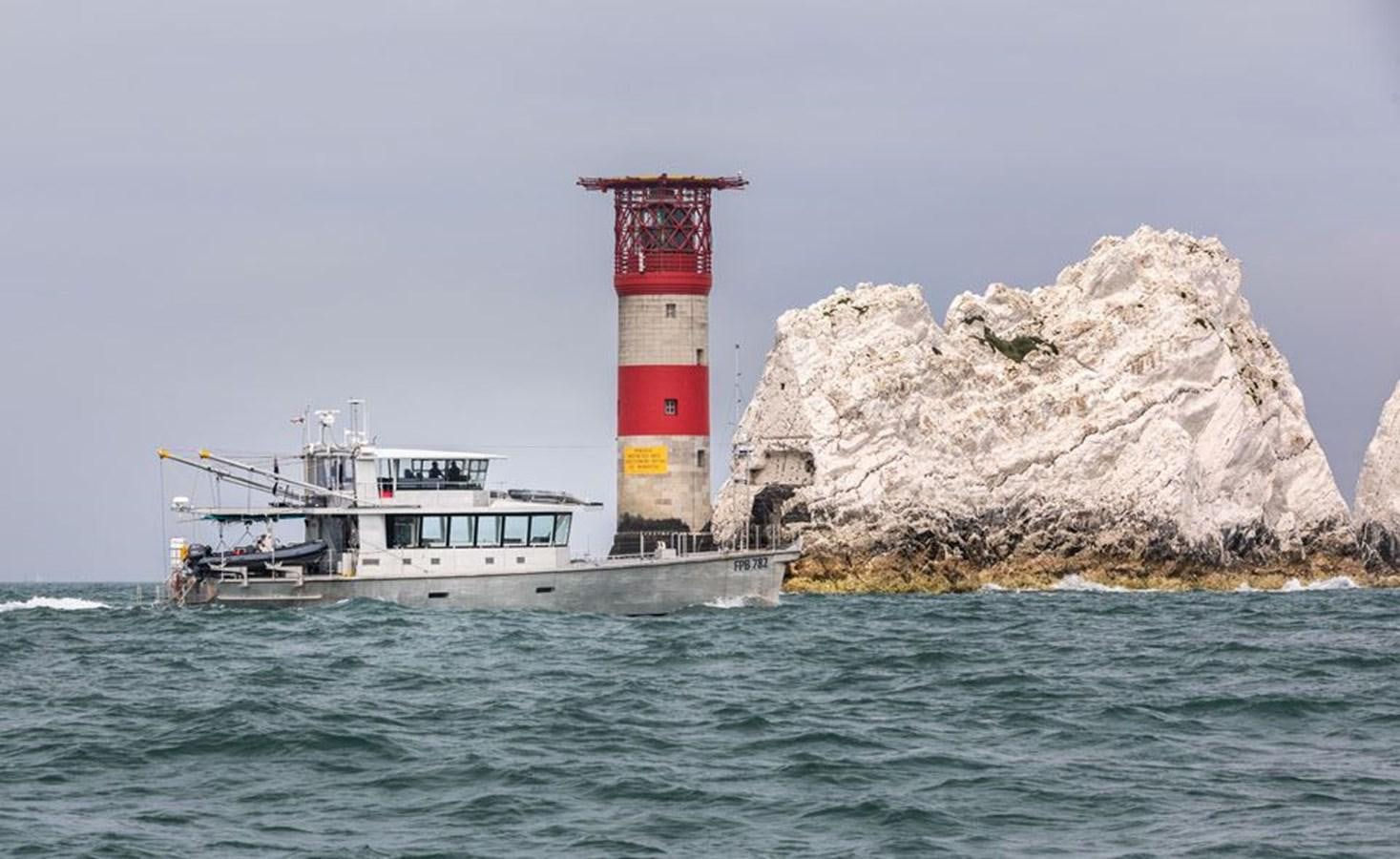a lighthouse next to a boat aboard GREY WOLF Yacht for Sale