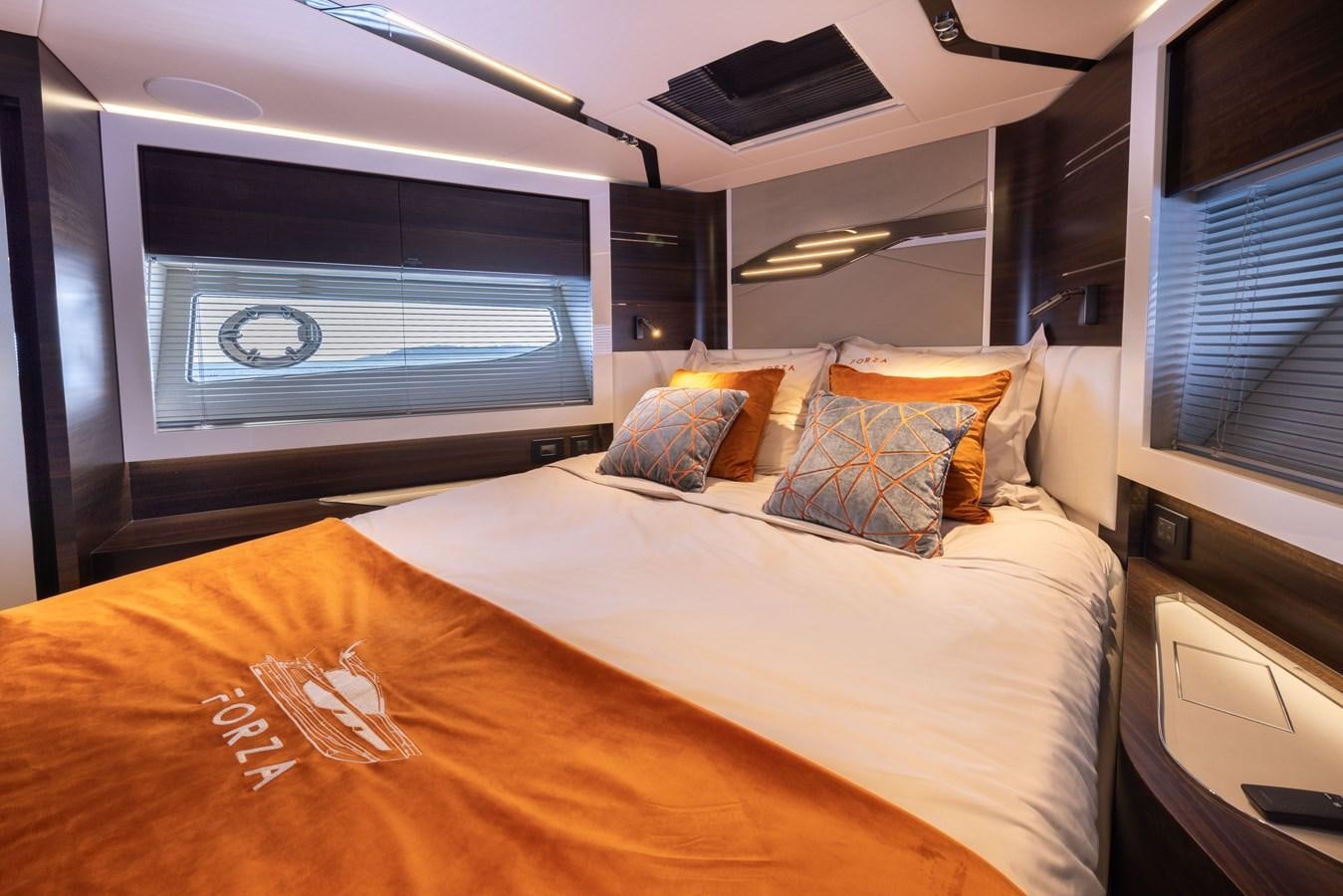 a bed with a white sheet and a television on the wall aboard FORZA Yacht for Sale
