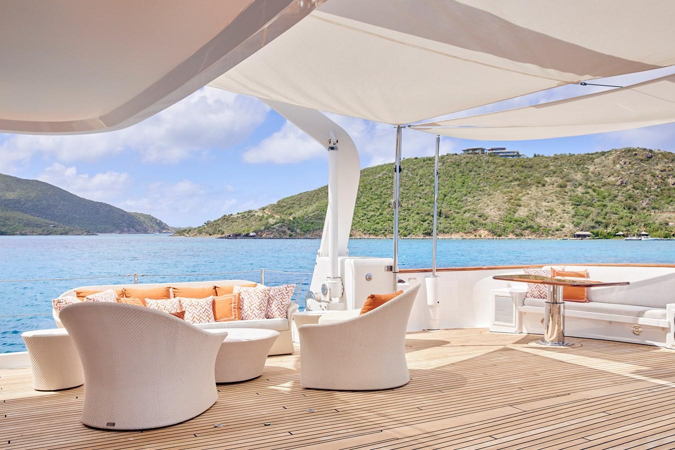a lounge area with a large body of water and a large white building with a white chair and aboard AMARA Yacht for Sale