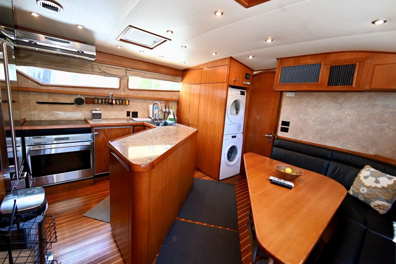 a kitchen with a table and a refrigerator aboard CAPTIVATOR Yacht for Sale