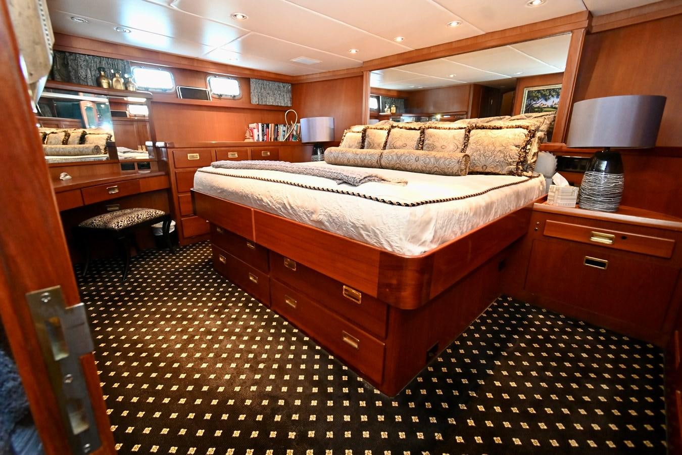 a bedroom with a bed and a lamp aboard CAPTIVATOR Yacht for Sale