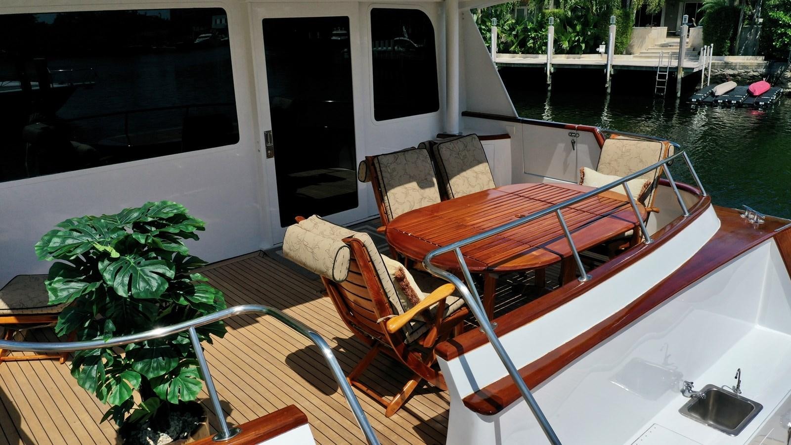 a deck with chairs and a table on it aboard CAPTIVATOR Yacht for Sale