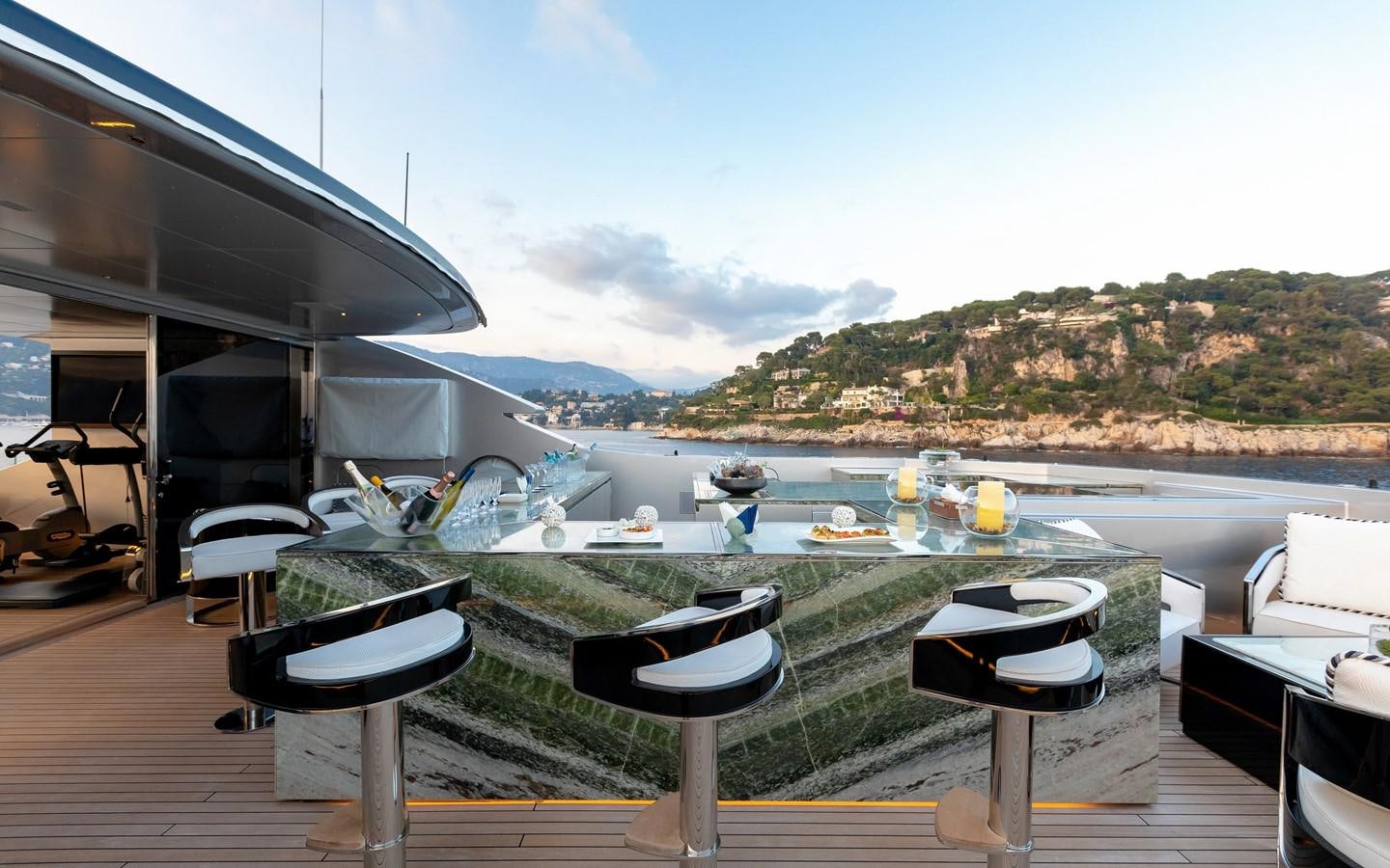 a deck with a table and chairs on it by a body of water aboard SARASTAR Yacht for Sale